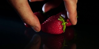 一个男人把草莓放在一张深色的桌子上