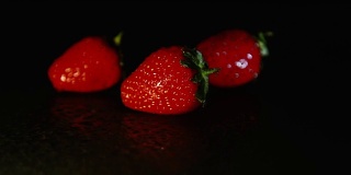 黑暗中，潮湿的地面上放着三个草莓