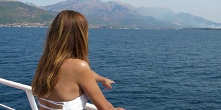 古铜色的年轻女子站在船上观察大海