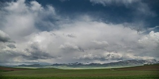 绿色的草地和地平线上的山脉在云。间隔拍摄4 k