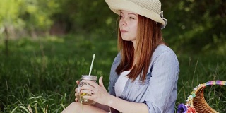 戴着帽子的女孩微笑着享受着冰凉的柠檬水