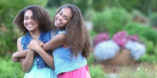 两个非裔美国姐妹在花园里微笑