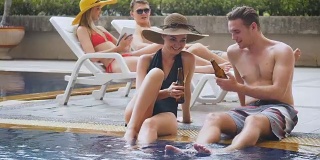 一群朋友喜欢在室外游泳池喝啤酒和鸡尾酒聊天，人们，度假和夏天的概念