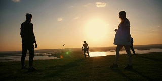 一群年轻的朋友在户外玩飞盘在夏天的日落