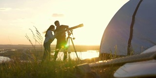 夏日日落时，年轻的朋友们在山上通过望远镜观看