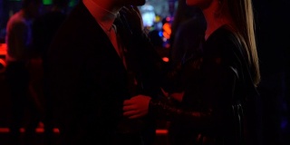 喝醉了的放松的男人在西装亲吻他的女朋友和跳舞在迪斯科俱乐部