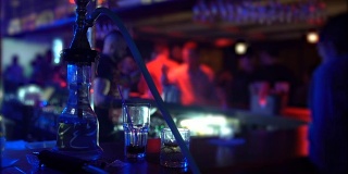 水烟和两个玻璃杯立在夜店吧台上，派对气氛