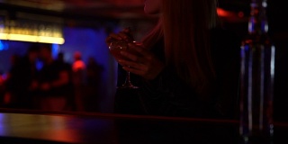 优雅的女子独自在酒吧喝着鸡尾酒，享受着音乐，轻松的氛围