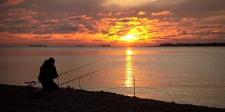 间隔拍摄。渔夫抓了一条鱼。壮丽的日落水上。