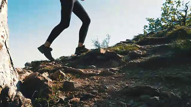 在山崖上徒步旅行的女旅行者的脚上的观点。走在岩石