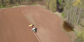 拖拉机在春季农田播种作物，鸟瞰图