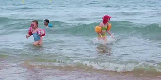 孩子们戴着充气圈奔向大海