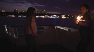 夜晚，两个美丽的年轻女子在甲板上跳舞的剪影。船上的闺蜜视频素材模板下载