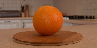 近距离观察整个橙子。以白色厨房为背景的旋转相机。Dolly-shot。