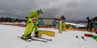 一个教练教一个小女孩如何滑雪。