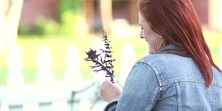 成熟的女人在前院拿着花园里的花