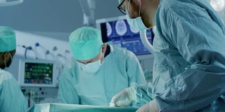 手术室的特写镜头，助理在手术中向外科医生发放器械。手术的进展。从事外科手术的专业医生。