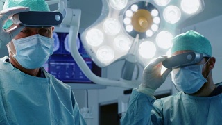 在高科技医院，外科医生戴上增强现实眼镜进行最先进的手术。在手术室工作的医生和助手。视频素材模板下载