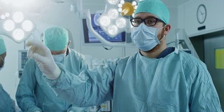 手术室外科医生在手术中使用增强现实技术的手势。在后台助理和护士使用真正的设备工作。