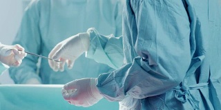 手术助手在手术中给外科医生发放器械的特写镜头。手术的进展。从事外科手术的专业医生。