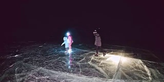 家庭是滑冰之夜。女孩和男孩在大自然中骑着花样滑冰鞋。母亲，女儿和儿子一起骑在裂缝的冰上。冬季户外运动对运动员来说是一种乐趣。