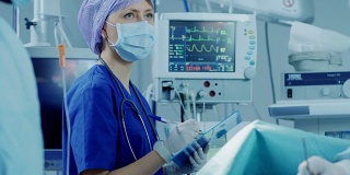 在医院的手术室里，麻醉师注视、监测和控制病人的生命体征，并向主刀医生点头示意继续手术。