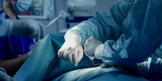 不同的专业外科医生团队在医院手术室对病人进行侵入性手术。外科医生使用和其他工具。