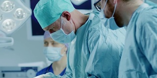 在医院的手术室里，专业的外科医生和护士组成了多样化的团队，缝合伤口后手术成功。
