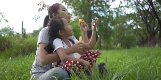 慢镜头，亚洲家庭是幸福的，母女和儿子在花园里吹泡泡联合活动。