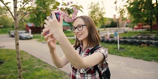年轻迷人的女人在眼镜与樱花自拍
