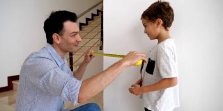 慈爱的父亲教他的儿子如何测量一堵墙指导他，看起来很自豪