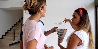 一对快乐的夫妇拿着调色板与室内设计师讨论墙壁的颜色