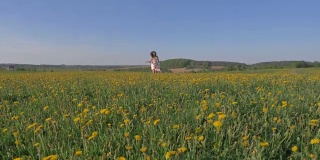 穿着漂亮的女人在田野里奔跑着，带着黄色的花朵，举起双臂