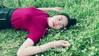 年轻的亚洲女子躺在草地上，动作缓慢视频素材模板下载