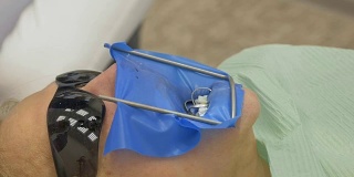 牙医在现代牙科诊所里治疗病人。牙齿矫正医师有一个助手。运行中采用围堰。客户正在做假牙。医生和助手戴着防护口罩工作。