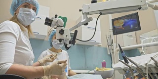 医生使用特制的口腔内微型数码相机检查牙齿。在监视器上，牙医和病人可以看到牙齿问题的视频。牙齿矫正医师使用显微镜。牙医在现代牙科诊所。