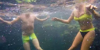 年轻的雄性和雌性浮在水下，头在海面上，水下摄像机