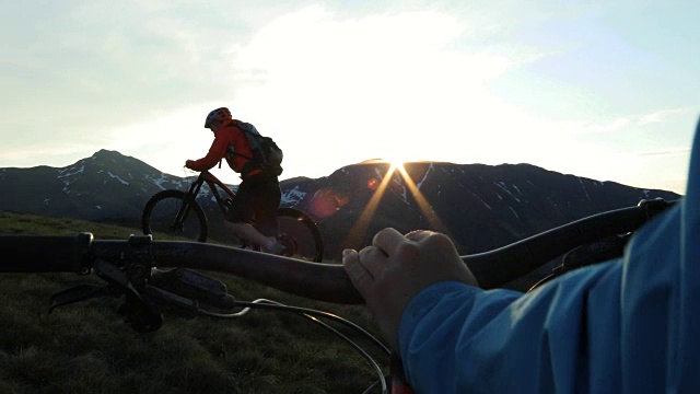 第一人称视角跟随另一个山地自行车手，因为他推动了在日出的高山斜坡。