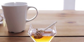 将热水倒入装有茶包和蜂蜜的杯子中