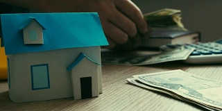 抵押贷款的概念。房子的模型和数钱的过程。房地产贷款。