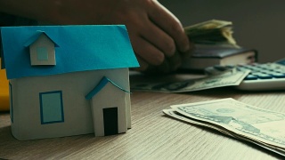 抵押贷款的概念。房子的模型和数钱的过程。房地产贷款。视频素材模板下载