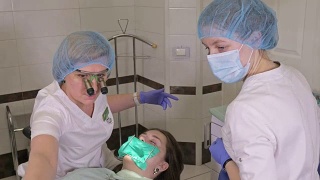 一名妇女在牙科诊所接受牙科治疗以补牙洞。牙科修复与复合材料聚合紫外光与激光。视频素材模板下载