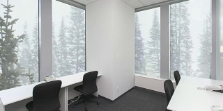 空荡荡的办公室，桌子上放着椅子和电话，窗外的森林里飘着雪花。背景板，色度键视频背景