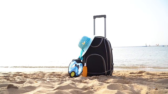 带着太阳镜、海星、草帽和沙滩拖鞋的旅游度假旅行箱，在美丽的棕榈树海滩上。旅行箱广告