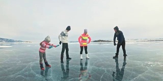 一家人在大自然的冰上进行体育锻炼。父亲在冬天训练他的家人。母女和儿子看着他的训练课。孩子们试着重复。运动前的标准拉伸。