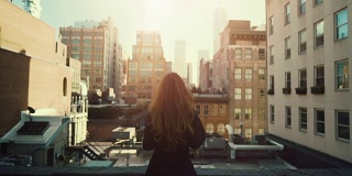 美丽的红发女人站在屋顶上的背影照片。城市城市景观纽约市与伟大的摩天大楼和建筑物。
