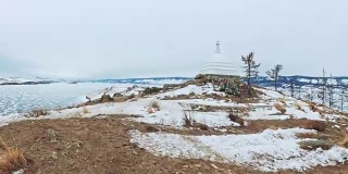 女人在贝加尔湖冰面上的旅行。观点的看法。闭关独特的佛塔布尔可汗纪念碑象征神秘的历史仪式岛大井山水山萨满教崇拜。冬岛之旅。