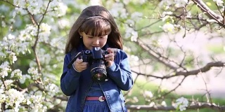 一个漂亮的小女孩手里拿着照相机。