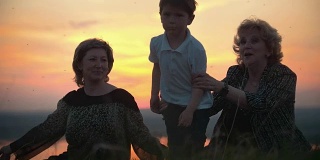 祖母，母亲和小儿子在山上拍蚊子日落