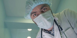 戴口罩的医生低头看着病人检查他的意识